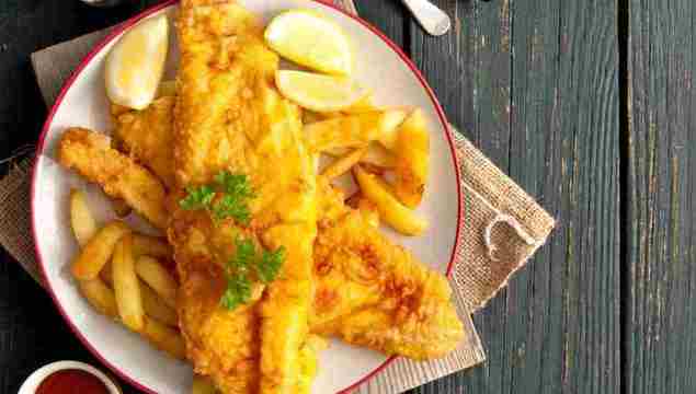 Two pieces of battered fish on a plate with chips.