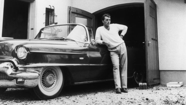 Welsh actor Richard Burton (1925 - 1984) leaning on a Cadillac convertible, circa 1955.