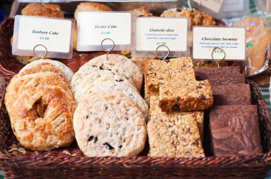 Hand made Banbury Cakes, Eccles Cakes, Granola Slices and Chocolate Brownies for sale on a stall at a UK Farmer’s Market.