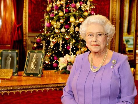 Britain\'s Queen Elizabeth II poses in the State Dining Room of Buckingham Palace after recording her Christmas Day television broadcast to the Commonwealth on December 10, 2014 in London. On the table are portraits of the Queen\'s grandfather King George V and Queen Mary along with a decorated brass tin given to all members of the British, Colonial and Indian Armed Forces for Christmas 1914 at the suggestion of their daughter Princess Mary. (Photo by John Stillwell - WPA Pool/Getty Images)