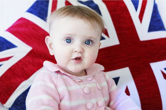 LONDON, ENGLAND - FEBRUARY 2: A wide eyed young infant looks directly at the viewer in curiosity set against the backdrop of the British flag, the Union Jack. on February 02, 2017 in London, United Kingdom.