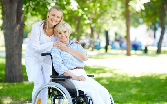 Adult care worker moving a client in a wheelchair.