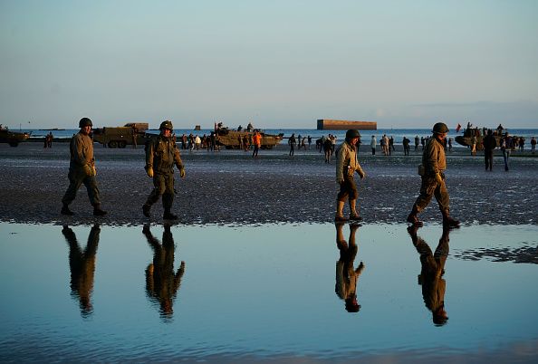 Military re-enactors walk along Gold Beach at Mulberry harbour on the morning of the 75th anniversary of the D-Day landings on June 6
