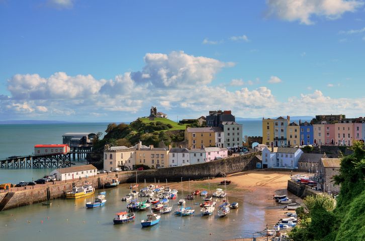 Picturesque view of boats in Tenby Harbour, with its clusters of colourful painted houses, and Castle Hill